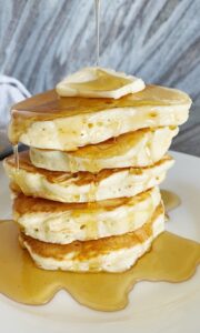 A stack of puffy pancakes dripping with syrup