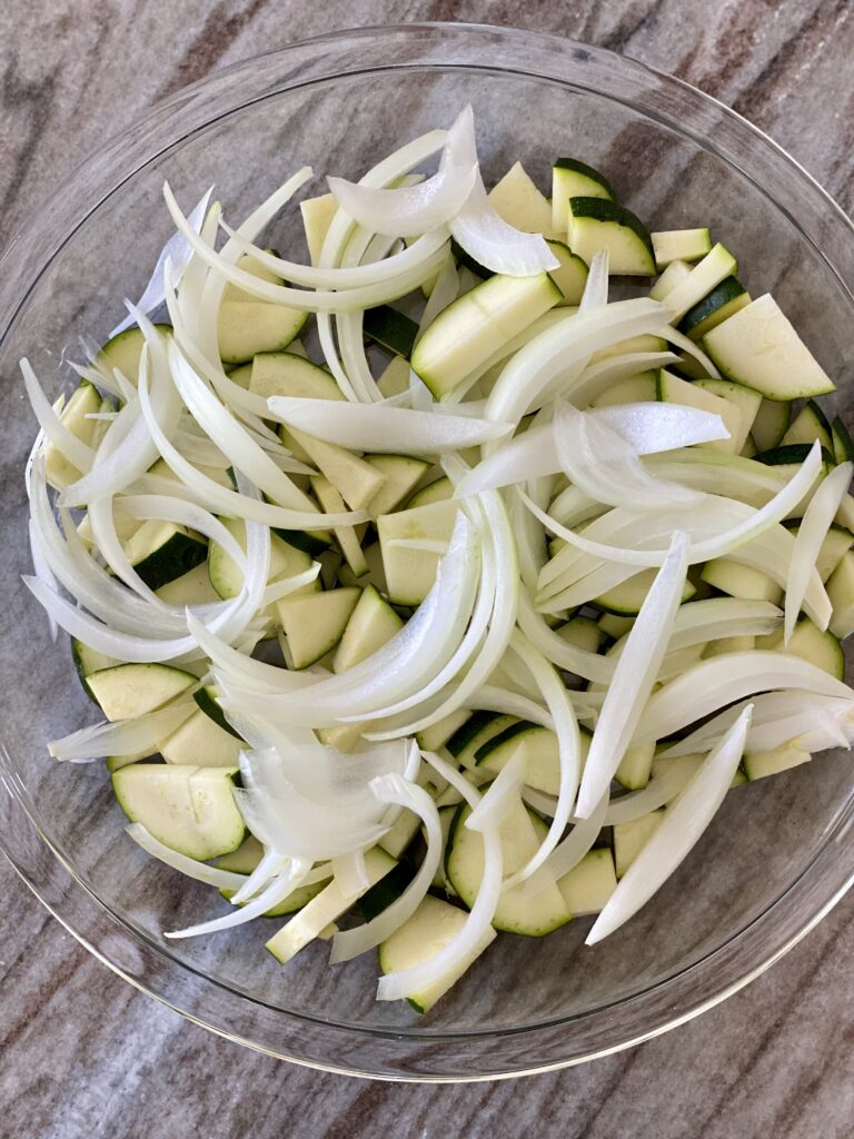 A picture of zucchini and onions layered in a baking dish