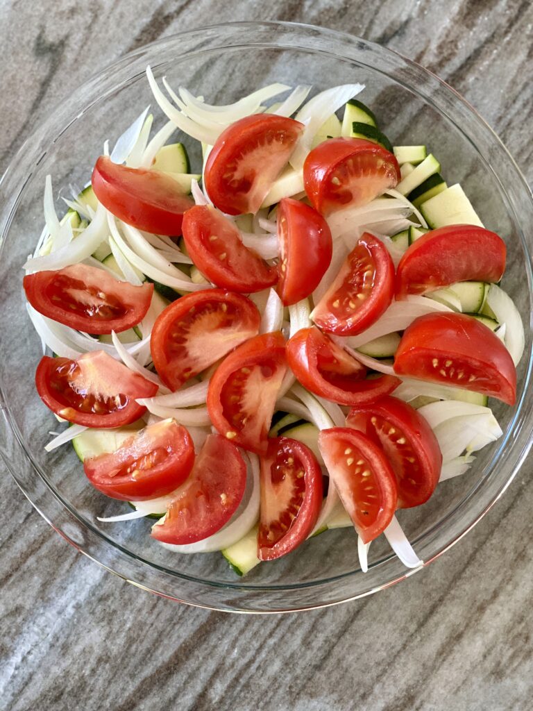A picture of zucchini and onions topped with tomato slices