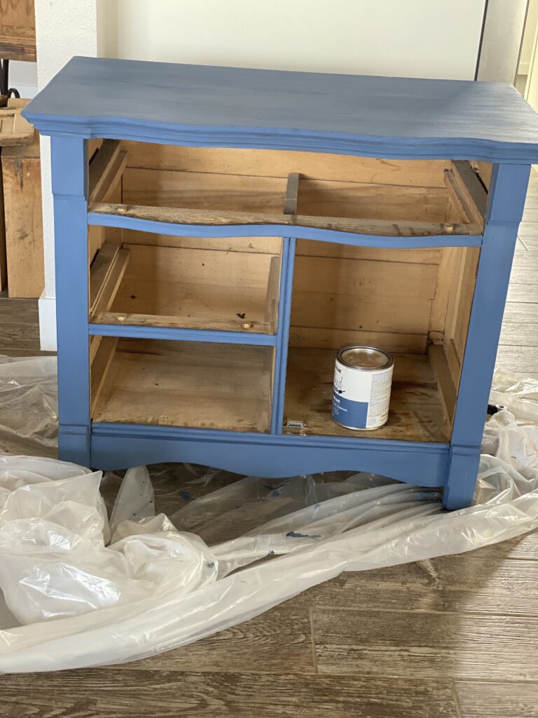 A picture of a dresser painted costal blue before the drawers are added.