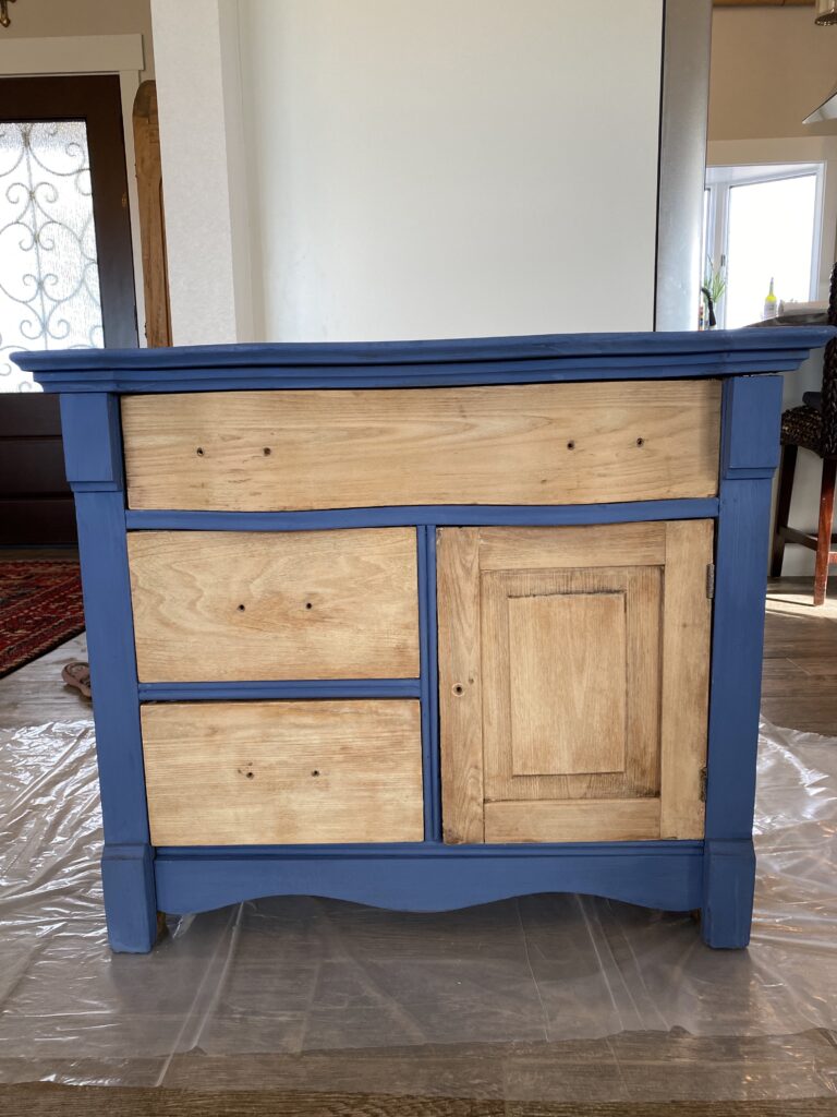 A picture of a dresser that is painted and has raw wood finishing on the drawers before it's waxed.
