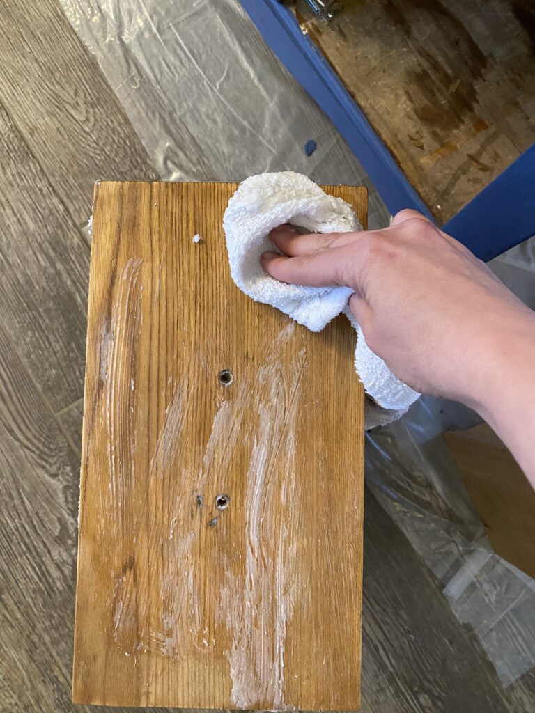 A picture of a hand applying wax to a dresser drawer. 